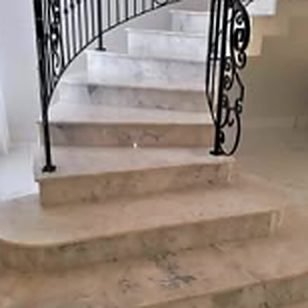 Escada curva revestida em mármore claro