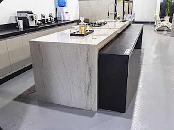 Ilha de cozinha em pedra branca com veios cinza e lateral em cascata